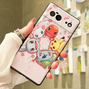 May include: Pink phone case with a design of five cartoon Pokemon characters, including Pikachu, Bulbasaur, Charmander, Squirtle, and Eevee. The case has a floral pattern and a black border.