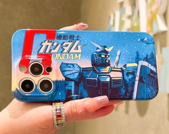 Può includere: Una custodia per telefono blu e rossa con un'illustrazione di un robot Gundam. La custodia ha uno sfondo bianco con un cielo blu e stelle. Il testo sulla custodia recita "機動戦士ガンダム" e "UNDAM".