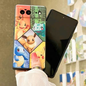 May include: A black phone case with a colorful design featuring Pokemon characters like Pikachu, Squirtle, Bulbasaur, and Eevee. The case has a cutout for the camera lens.