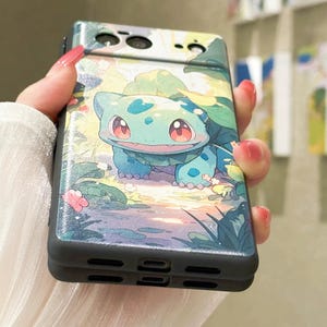 May include: A black phone case with a green cartoon character on a light blue background. The character is surrounded by green leaves and flowers. The phone case has a camera lens on the back.
