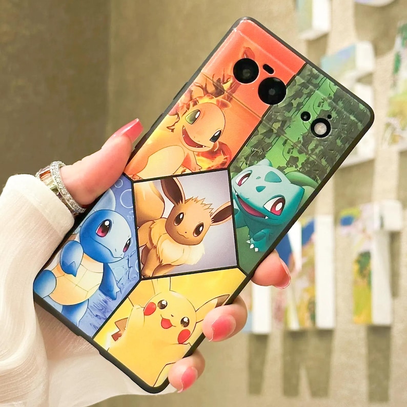 May include: A black phone case with a multi-colored design featuring different Pokemon characters. The case has a camera lens cutout and a textured surface.