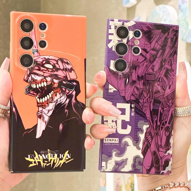 Może przedstawiać: Dwa etui na telefon z kolorowym wzorem anime. Etui po lewej stronie przedstawia czerwonego i czarnego robota z napisem "EVANGELION" w języku japońskim. Etui po prawej stronie przedstawia fioletowego robota z napisem "SENPAI LIMITED EDITION" w kolorze białym.