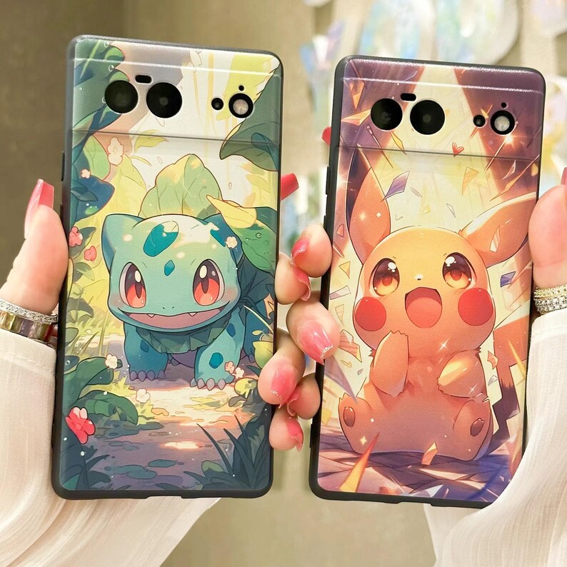 May include: Two phone cases with colorful cartoon character designs. The left case features a green and blue creature with a red eye. The right case features a yellow creature with a red eye and a yellow background.