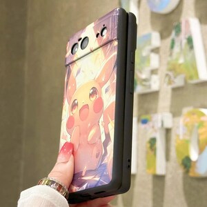 May include: A black phone case with a colorful illustration of Pikachu, a popular Pokemon character, on the back. The case has a raised camera bump and a black border.