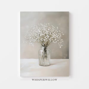 May include: A still-life print featuring a clear glass jar filled with water and a bouquet of white baby's breath flowers. The artwork has a neutral color palette with a soft, blurred background and the text "WHISPERWILLOW" at the bottom.