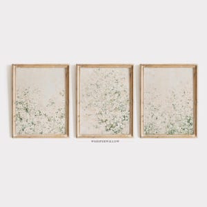 May include: A set of three rectangular wall art prints in light wooden frames. Each print features an abstract botanical design with white and sage green textured paint strokes on a cream background. The text WHISPERWILLOW is centered below.