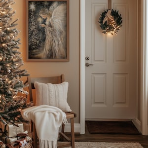 May include: A cosy living room with a Christmas tree, a chair with a white throw blanket, and a framed painting of an angel holding a candle. A wreath with lights hangs on the door.