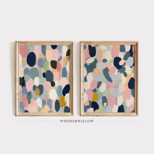 Pode incluir: Duas pinturas abstratas emolduradas com um design abstrato colorido, incluindo cores rosa, azul, verde e amarelo. As pinturas são de estilo moderno e ficariam ótimas em uma sala de estar ou quarto.