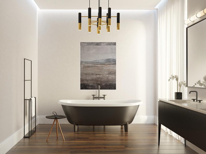 K&ouml;nnte beinhalten: Ein modernes Badezimmer mit einer freistehenden Badewanne in Dunkelgrau, einem schwarzen Waschtisch und einem schwarz-goldenen Kronleuchter. Ein Landschaftsbild h&auml;ngt &uuml;ber der Wanne. Der Raum hat Holzb&ouml;den.