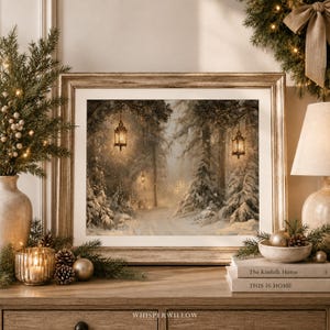 May include: A framed landscape print depicting a snowy forest path at twilight, illuminated by hanging lanterns. The artwork is displayed in a light-toned wooden frame, resting on a surface with decorative pine branches and books.