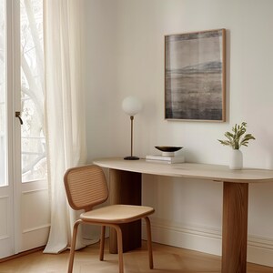 K&ouml;nnte beinhalten: Ein heller Holzschreibtisch mit abgerundeter Kante, eine braune Metalllampe mit wei&szlig;er Kugel und ein gerahmtes Landschaftskunstwerk. Ein Stuhl mit Flechtwerk und eine wei&szlig;e Vase mit Gr&uuml;n sind ebenfalls zu sehen.
