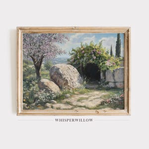 Könnte beinhalten: Gerahmtes Landschaftsgemälde, das eine ruhige Szene im Freien zeigt. Ein Steinweg führt zu einem gewölbten Eingang, der mit rosa und weißen Blumen geschmückt ist. Ein großer Felsbrocken und ein blühender Baum befinden sich auf der linken Seite. Das Gemälde ist in einem hellen Holzrahmen.