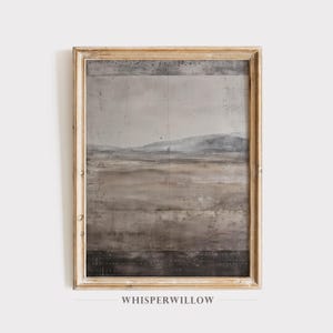 K&ouml;nnte beinhalten: Ein gerahmter Landschaftskunst-Druck mit ged&auml;mpften Farben. Das Kunstwerk zeigt eine Bergkette und ein Feld in Grau-, Braun- und Beiget&ouml;nen. Der Rahmen ist hellgoldfarben und leicht verwittert. Der Text "WHISPERWILLOW" befindet sich unten.