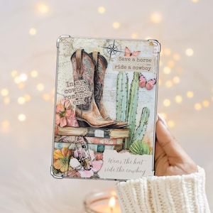 以下が含まれることがあります： カウボーイブーツのデザインが施された装飾用の長方形のアイテム。画像には「In my cowboy romance era」、「Save a horse ride a cowboy」、「Wear the hat ride the cowboy」というテキストが含まれています。デザインには、コンパス、サボテン、蝶が組み込まれています。