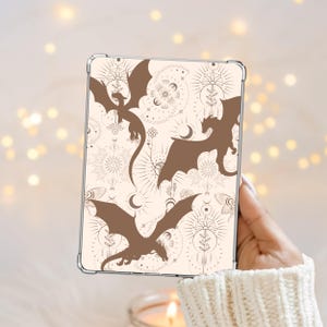 May include: A clear tablet case featuring a cream-coloured background with a repeating pattern of brown dragon silhouettes, celestial suns, moons, stars, and botanical line art elements arranged in a decorative, symmetrical layout.