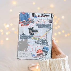May include: A clear phone case featuring a hockey-themed design. The design includes a blue jersey, hockey skates, a hockey stick, and the text "The New", "In My Hockey Romance Era", and "Hockey boys do it better".