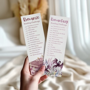 May include: Two rectangular paper bookmarks featuring reading challenge lists. The left bookmark is titled Romance Reading Challenge with a floral and book illustration. The right bookmark is titled Romantasy Reading Challenge with a dragon illustration.