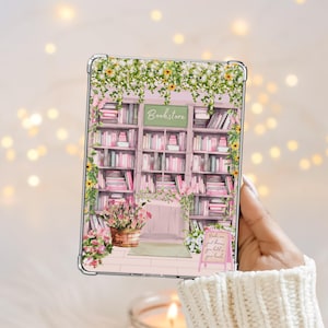 May include: A clear tablet case featuring a printed illustration of a bookstore interior with shelves filled with pink books, green vines, yellow flowers, and a sign that reads Bookstore. A small pink sign in the foreground reads Books are just dreams you hold in your hands.