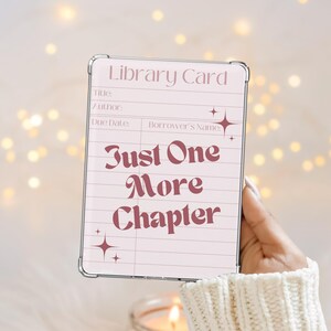 May include: A light pink library card design with the text "Just One More Chapter" in a burgundy script. The card has lines for title, author, due date, and borrower's name. The background is a soft, blurred bokeh.