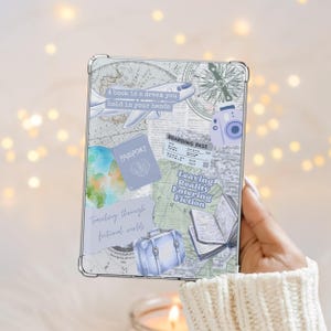 Könnte beinhalten: Eine transparente Tablet-Hülle mit einem Reise-Thema-Design. Die Hülle hat einen Weltkartenhintergrund mit Illustrationen von Reisepass, Flugzeug, Koffer und Kamera. Der Text enthält "A book is a dream you hold in your hands" und "Leaving Reality Entering Fiction."