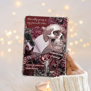 May include: A rectangular e-reader case featuring a dark red and black collage design with a human skull, a black raven, open book pages, and deep red roses. Text reads: Morally gray is my favourite colour, Reading Something Unholy, and When I die delete my Kindle history.
