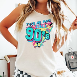 Puede incluir: Camiseta sin mangas de color marfil con un gráfico colorido de los años 90. El gráfico dice "TAKE ME BACK TO THE 90's" en turquesa, rosa y amarillo. El diseño incluye un patín y una cinta de cassette. La camiseta sin mangas es sin mangas.