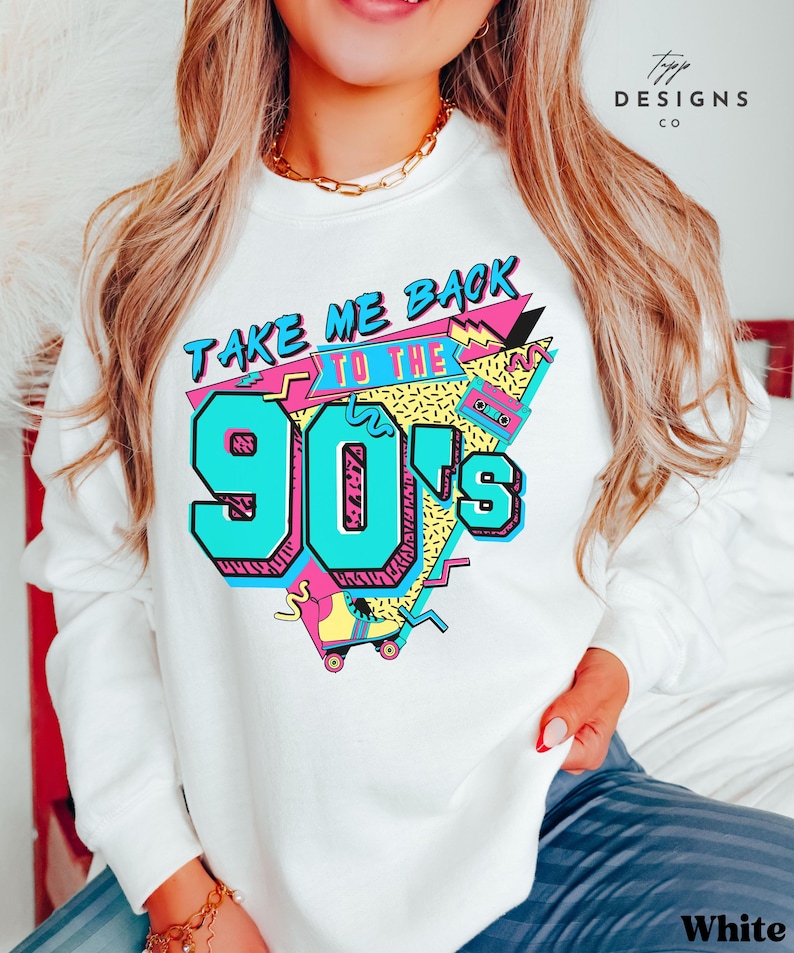 Puede incluir: Sudadera blanca con un estampado gr&aacute;fico del texto "Take Me Back to the 90's" en un estilo retro colorido. El gr&aacute;fico incluye un pat&iacute;n, una cinta de casete y formas geom&eacute;tricas.