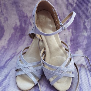 Könnte beinhalten: Ein Paar lavendelfarbene Tanzschuhe mit gekreuzten Riemen und einer Wildledersohle.