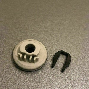 May include: A white plastic washer with a small hole in the center and three tabs on the side, next to a black metal u-shaped clip.