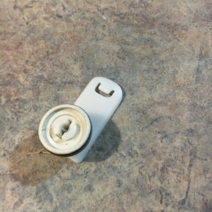 May include: A white plastic washer with a round, white knob and a small, white tab on the side.