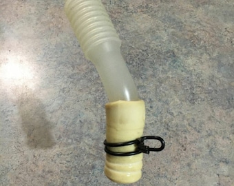 May include: A white plastic tube with a beige rubber end and a black clamp. The tube is bent at a 90-degree angle.