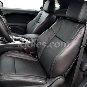 May include: Black leather car seats with a black leather steering wheel. The seats have a diamond pattern and the steering wheel has a silver trim.