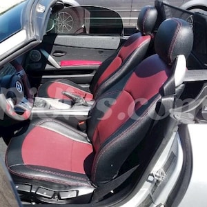 Puede incluir: El interior de un coche convertible con asientos de cuero negro y costuras rojas. Los asientos están en las posiciones del conductor y del pasajero.