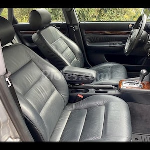 May include: A black leather interior of a car with a silver gear shift knob and a black leather armrest.