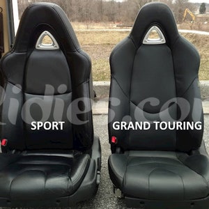 Puede incluir: Dos asientos de coche de cuero negro, uno etiquetado como "SPORT" y el otro como "GRAND TOURING".