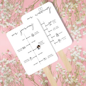May include: Two white paper fans with wooden handles, featuring timelines for a wedding. One fan is titled "our journey" and the other "our wedding." The timelines include dates, icons, and text, such as "First Date," "Proposal," and "Wedding."