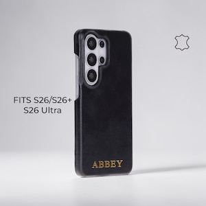 May include: Black leather phone case with the word "ABBEY" in gold lettering. The case is designed for S26, S26+, and S26 Ultra models. A leather symbol is visible in the upper right corner.