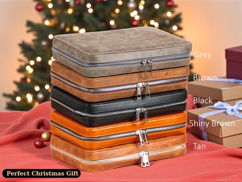 May include: A stack of zippered cases in various colors: grey, brown, black, shiny brown, and tan. Each case has a silver zipper. The cases are stacked on a red surface, with a Christmas tree in the background. The text "Perfect Christmas Gift" is at the bottom.