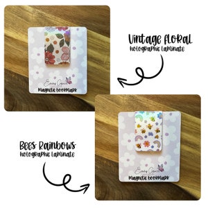 Puede incluir: Dos marcadores magn&eacute;ticos con acabado laminado hologr&aacute;fico. El primer marcador presenta un dise&ntilde;o floral vintage con flores rosas, rojas y naranjas. El segundo marcador presenta un dise&ntilde;o de abejas y arco&iacute;ris con colores amarillos, azules y verdes. Ambos marcadores tienen un fondo blanco con un patr&oacute;n floral morado claro.