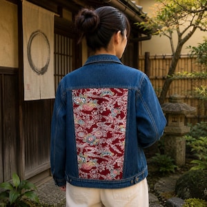 以下が含まれることがあります： 深い赤色の生地に多色の花と波の模様が施された大きな長方形のバックパネルが特徴の青いデニムジャケット。このジャケットには、クラシックな襟、長袖、ボタン付きの袖口、そして前面のボタン留めが付いています。