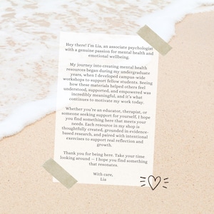 May include: A white rectangular paper note featuring black printed text that begins with Hey there! I'm Lia, an associate psychologist with a genuine passion for mental health and emotional wellbeing. The note is secured with two pieces of beige tape.