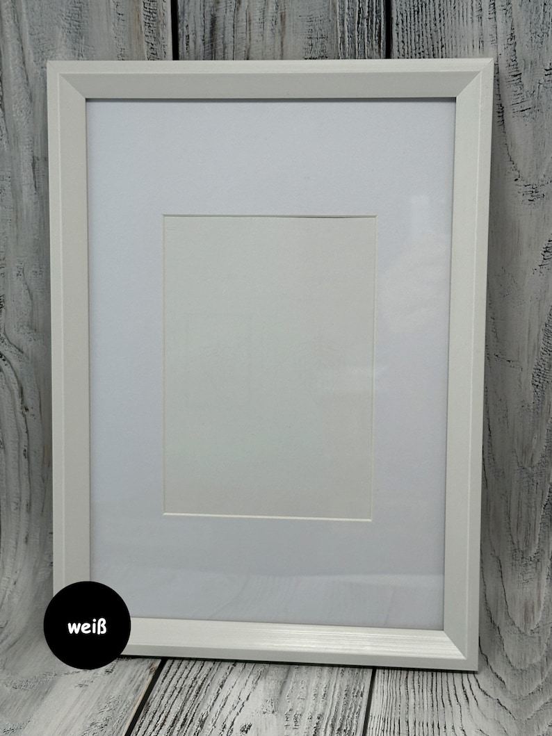 May include: A white picture frame with a white mat. The frame is on a white wood background. The word "wei&szlig;" is written in black on a white circle in the lower left corner of the image.