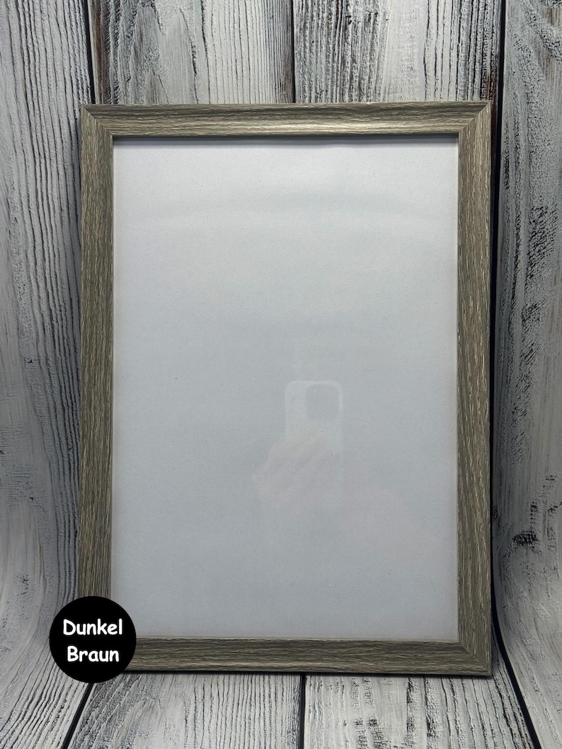 May include: A gray wood picture frame with a white mat. The frame is on a white wood background.