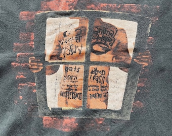 May include: A dark gray t-shirt with a vintage-style print of a window with four panes. Each pane has a different image and text, including "Daughter" and "Blood Sugar". The text "pearl jam" is printed in white at the top of the shirt.