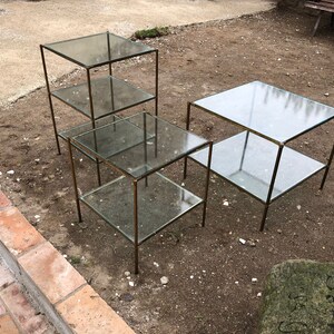 Puede incluir: Tres mesas de vidrio con marcos de metal. Las mesas son de diferentes tamaños y tienen dos estantes cada una.