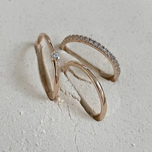 Pu&ograve; includere: Tre anelli d'oro con piccoli diamanti. L'anello superiore ha un solo diamante al centro. L'anello intermedio ha una fila di piccoli diamanti. L'anello inferiore &egrave; liscio.