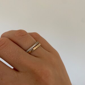 Pu&ograve; includere: Due anelli d'oro su un dito. L'anello superiore &egrave; una fascia sottile con piccoli diamanti. L'anello inferiore &egrave; una fascia pi&ugrave; spessa con una superficie testurizzata.