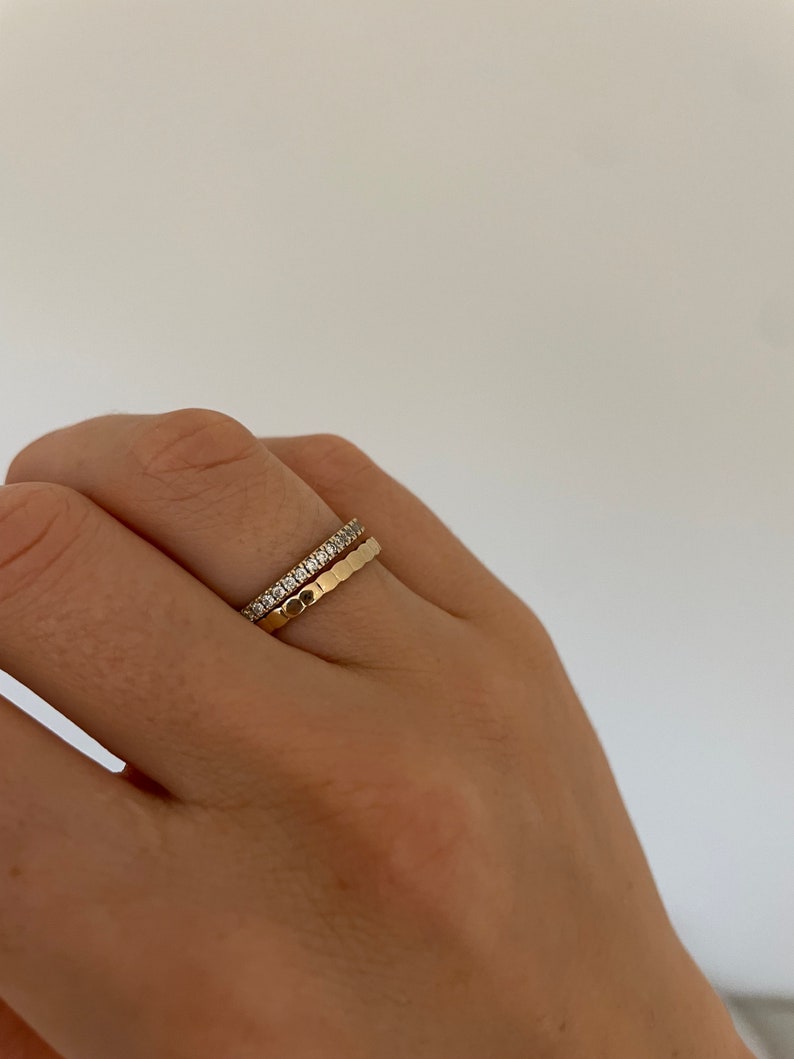 Pu&ograve; includere: Due anelli d'oro su un dito. L'anello superiore &egrave; una fascia sottile con piccoli diamanti. L'anello inferiore &egrave; una fascia pi&ugrave; spessa con una superficie testurizzata.