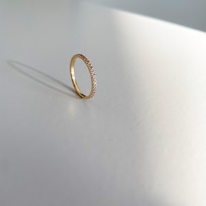 Pu&ograve; includere: Un sottile anello a fascia d'oro con piccole pietre trasparenti incastonate su tutta la fascia.