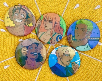 May include: Five circular pin-back buttons featuring illustrated anime-style characters. The top left button shows a smiling character with a straw hat, the top middle shows a character with orange hair, the top right shows a green-haired character, the bottom left shows a character with a long nose, and the bottom right shows a blonde character.